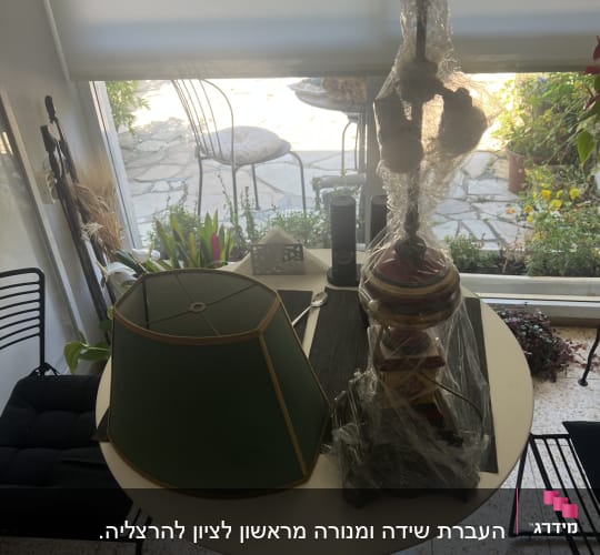 שולחן עגול עם אהיל ירוק וחפצים עטופים בניילון